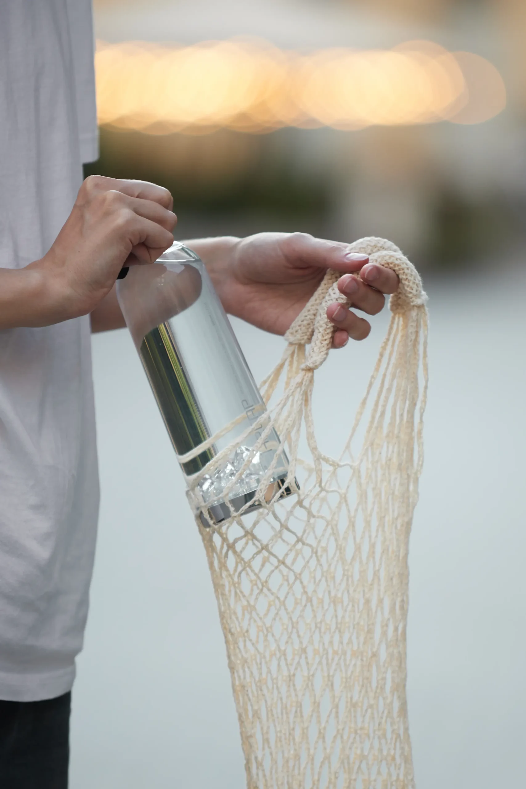 H2CAP PLUS hydrogen water bottle carried in a mesh bag